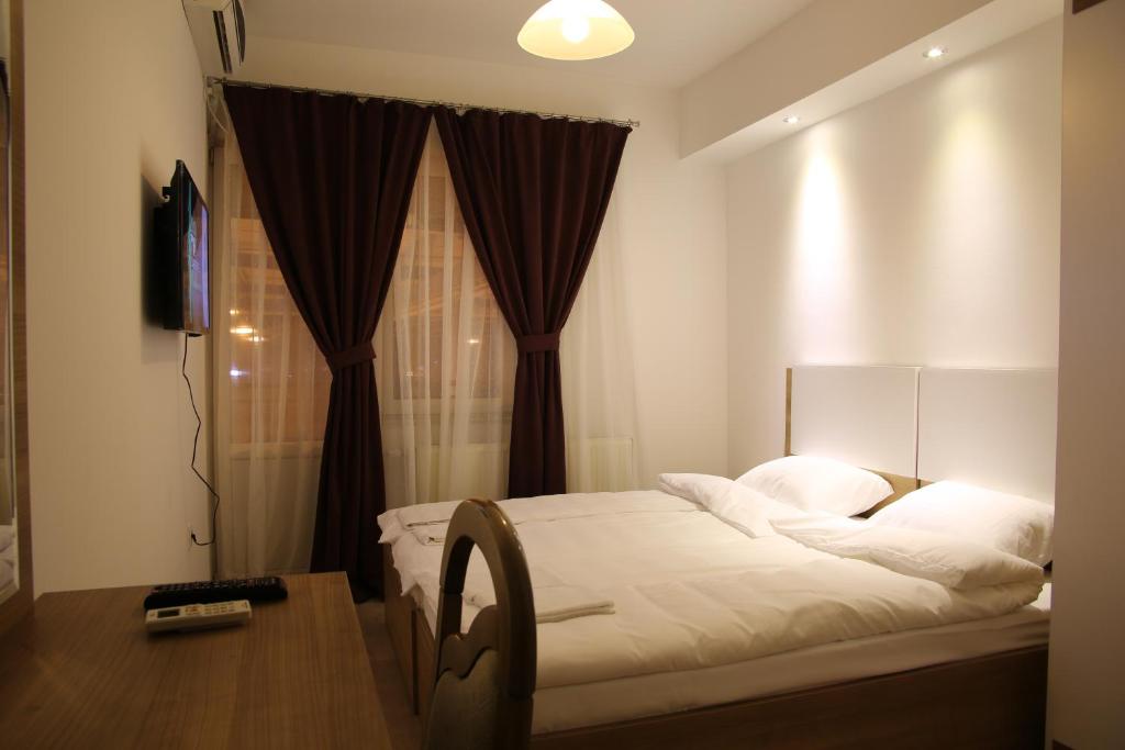 een slaapkamer met een bed, een bureau en een televisie bij Hotel Rio in Pristina