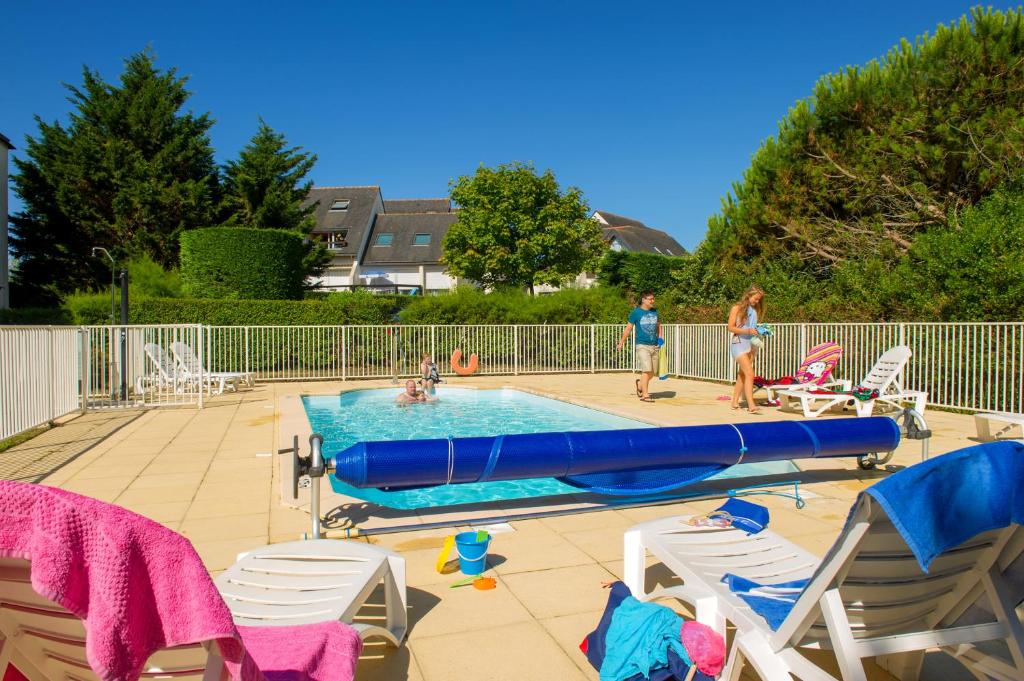 dos personas de pie junto a una piscina con una balsa azul en Résidence Goélia Bleue Océane, en Carnac