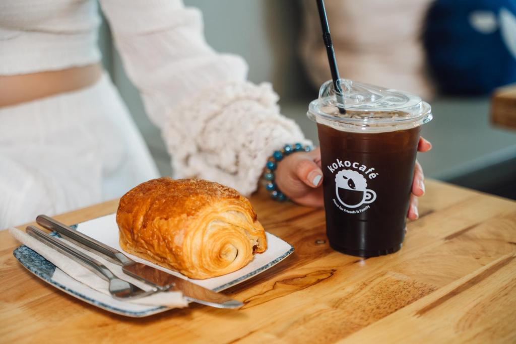 A croissant and iced coffee served at a wooden café table.