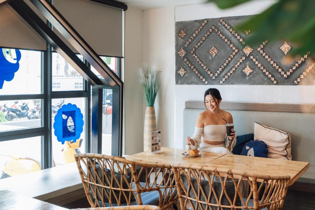 Casual communal table beside full-height windows in a bright hotel lounge.