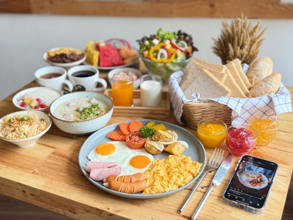 A generously styled breakfast spread with eggs, sausage, bread, fruit, drinks, and porridge.
