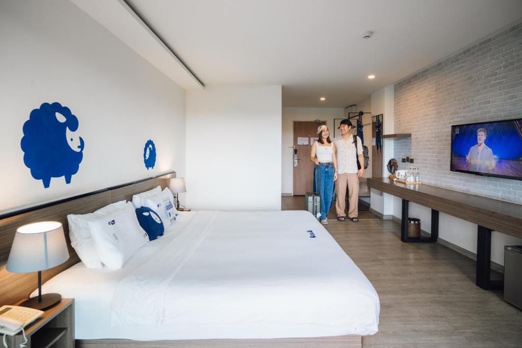 A spacious-looking double room pairs a large bed with a wall-length desk and television.