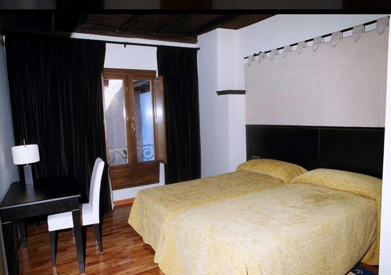a bedroom with a bed and a desk and a bed sidx sidx sidx at Posada Arco de San Miguel in Calatayud