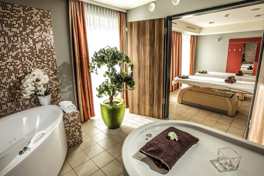 ein Badezimmer mit einer Badewanne und einem großen Spiegel in der Unterkunft Seehotel Fleesensee in Göhren-Lebbin