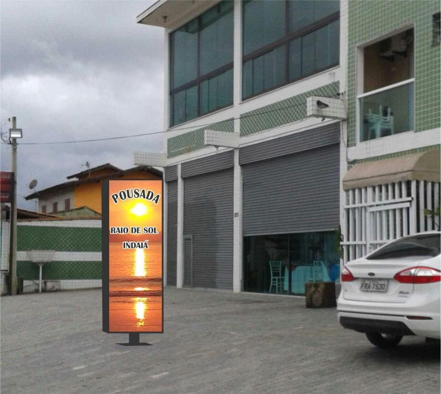 a sign in a parking lot in front of a building at Pousada raios de sol indaia in Bertioga