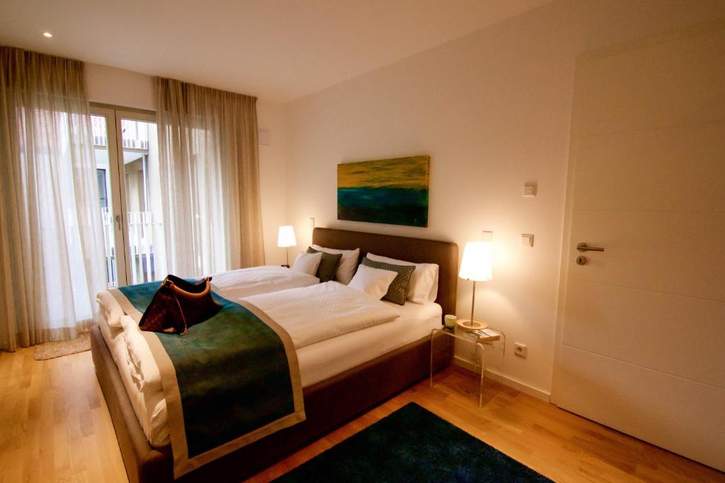 ein Schlafzimmer mit einem großen Bett mit zwei Lampen und einer Tür in der Unterkunft Donaupromenade in Regensburg