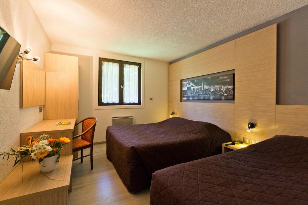 Habitación de hotel con 2 camas y mesa en Logis Albhotel Grill, en Alby