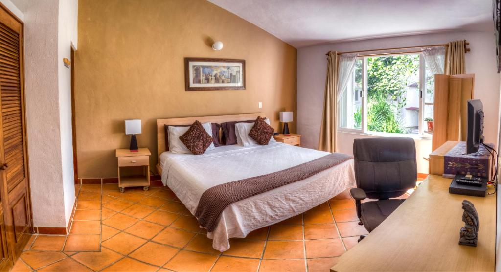a bedroom with a bed and a television and a window at Casa Mi Tesoro in Playa del Carmen