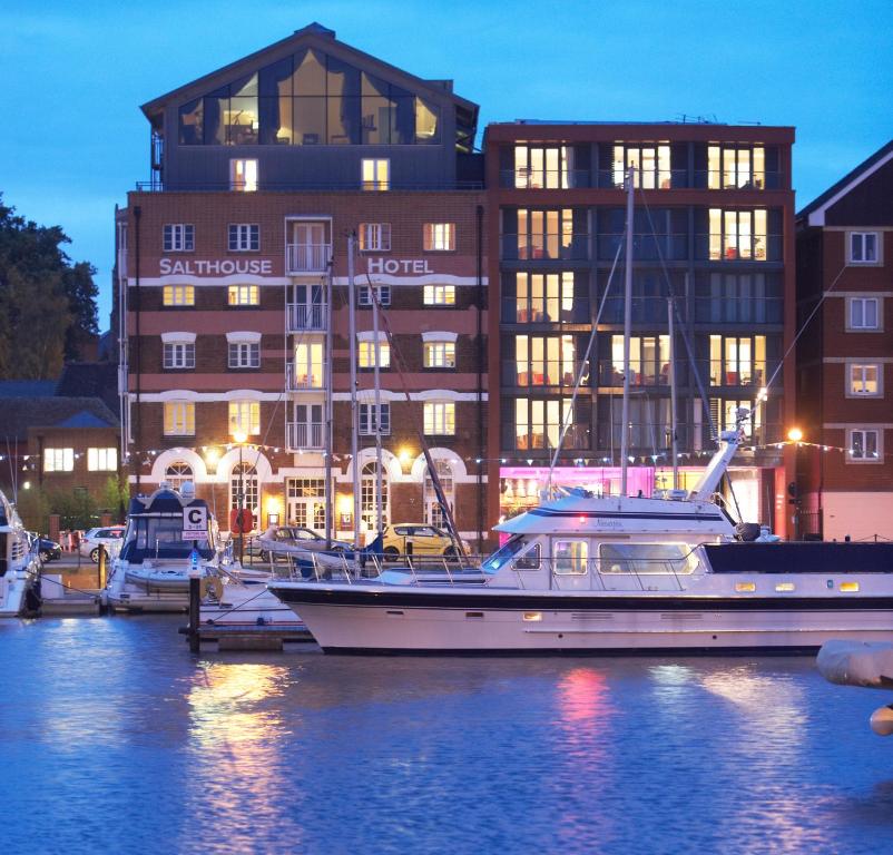 ein im Wasser vor einem Gebäude angedocktes Boot in der Unterkunft Salthouse Harbour Hotel in Ipswich