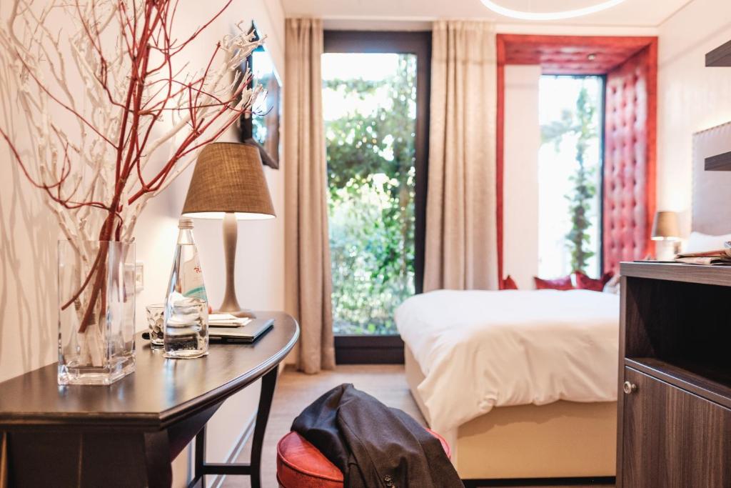 ein Hotelzimmer mit einem Bett und einem Schreibtisch mit einer Lampe in der Unterkunft Eriks Hotel in Fürholzen