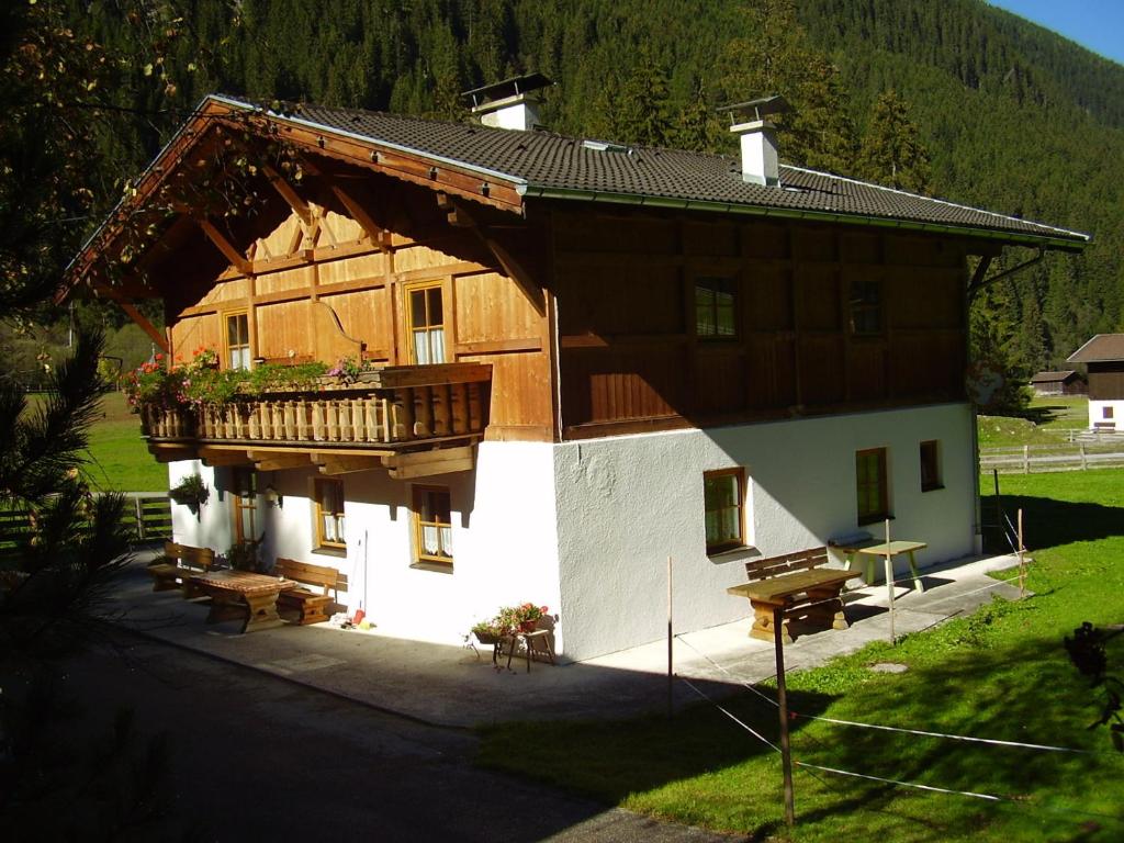 a large wooden house with a balcony and benches at Kartnall´s Alm in Neustift im Stubaital