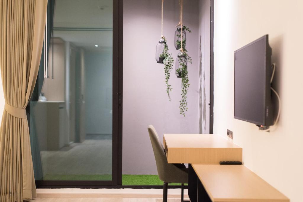 A wall-mounted television faces a narrow desk beside glazed bathroom doors.