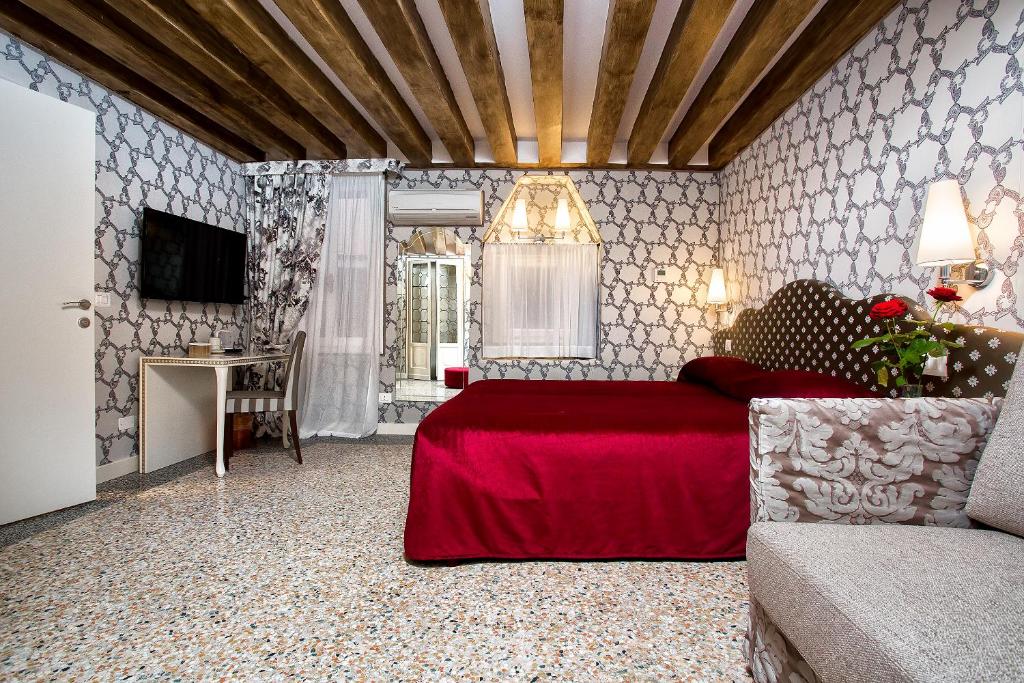 a bedroom with a red bed and a table and a television at Hotel Ca' Nobile Corner in Venice