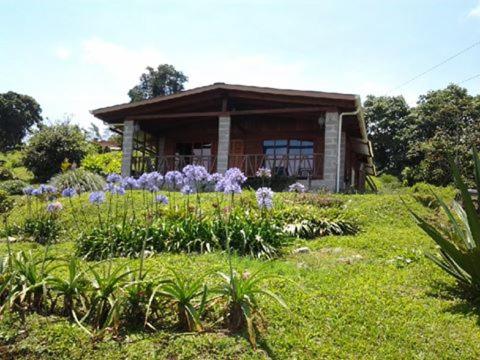 una pequeña casa con flores delante en Finca Y Granja Loma Bonita, en Turrialba