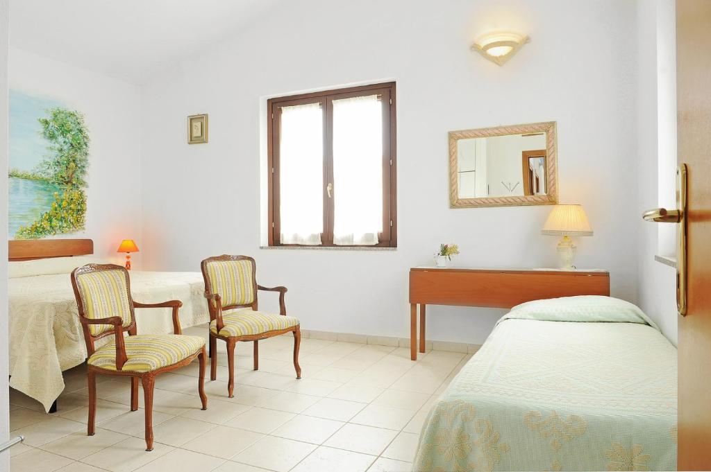 a room with two beds and a table and two chairs at Il Giardino di Valentina in Escolca