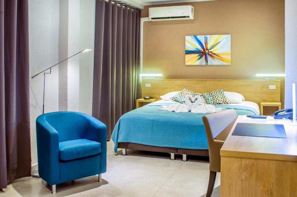 Habitación de hotel con cama y silla azul en Q-Inn Boutique Hotel en Paramaribo