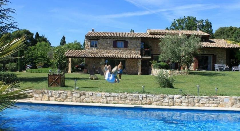 two people standing in front of a house next to a swimming pool at Suite de l'olivier au Mas au Coeur de la Provence &SPA in Saint-Cannat