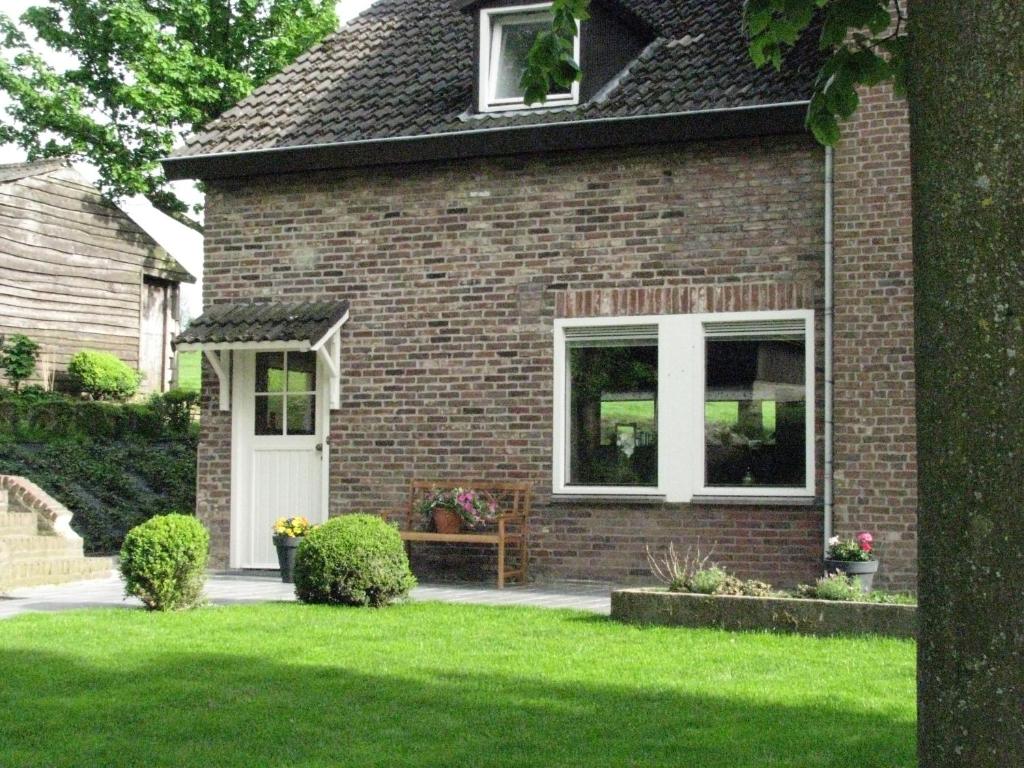 a brick house with a bench in the front yard at Vakantiewoning Kleijnen in Noorbeek