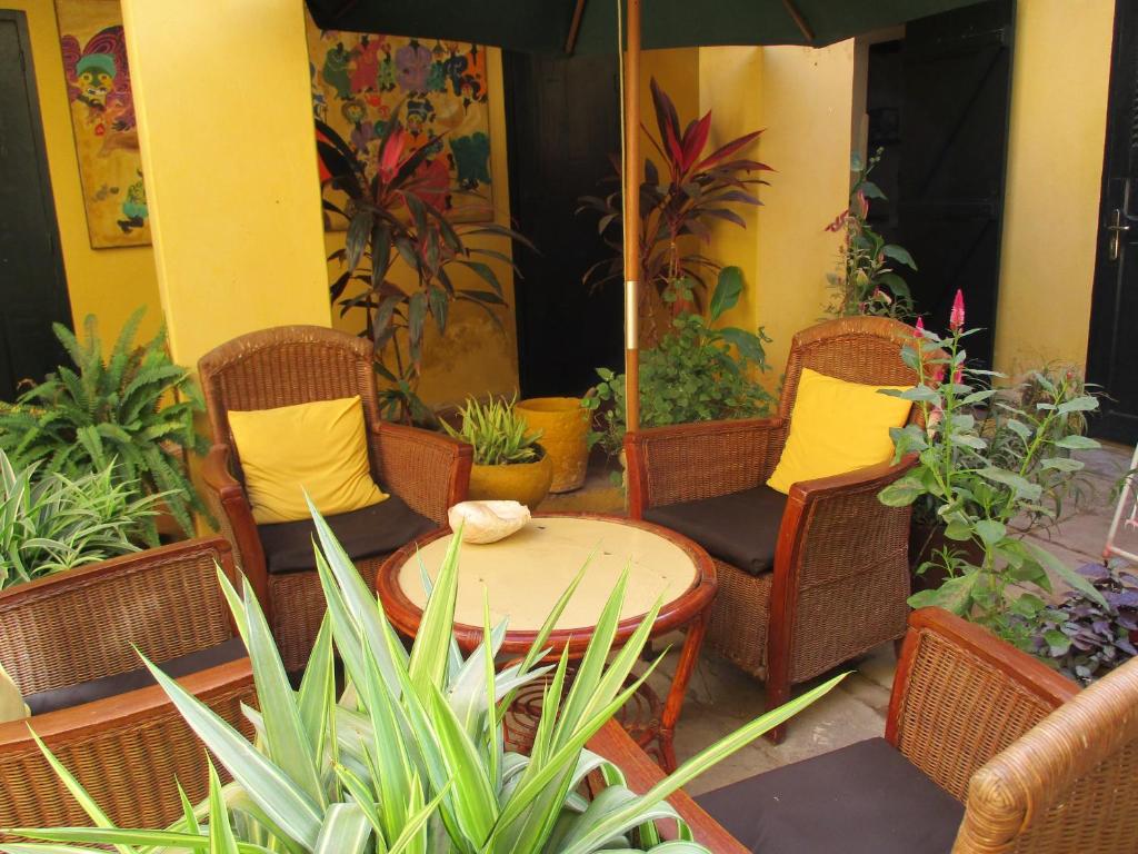 un patio con sillas, una mesa y algunas plantas en Chez Eric, en Gorée