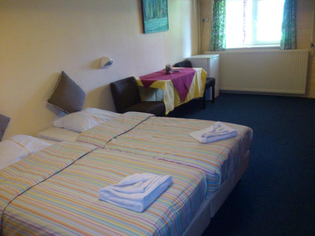 a hotel room with a bed with towels on it at Hostel Herberg de Esborg Scheemda in Scheemda