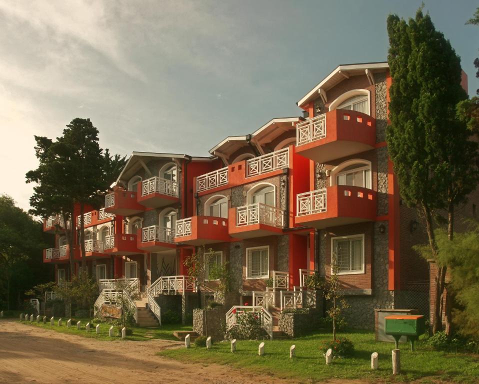 un gran edificio rojo con balcones blancos en el Apart Paradisso de Villa Gesell