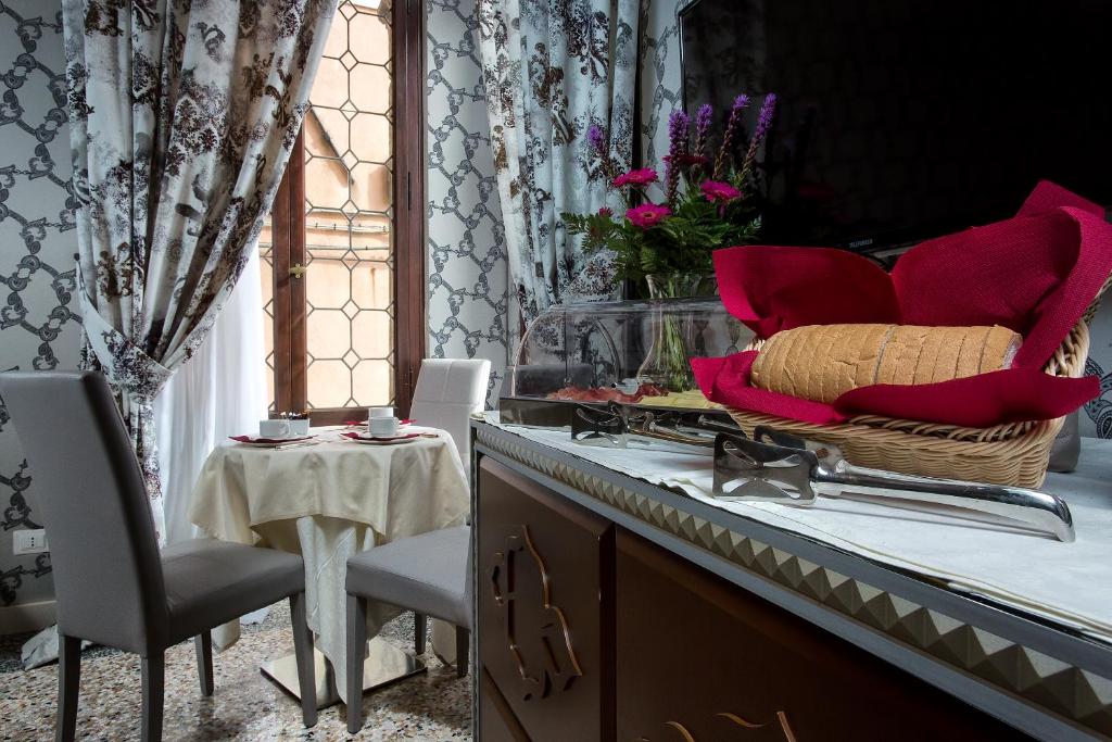 a buffet with red pillows and a table with chairs at Hotel Ca' Nobile Corner in Venice