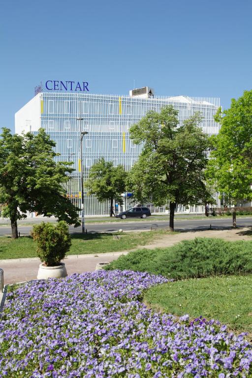 un parque con flores púrpuras frente a un edificio en Garni Hotel Centar, en Novi Sad