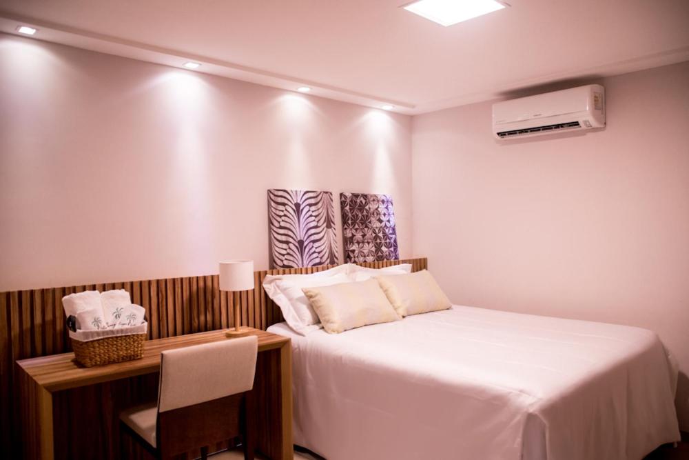 a small room with a bed and a desk with a heater at Village Hotel Pousada in Guamaré