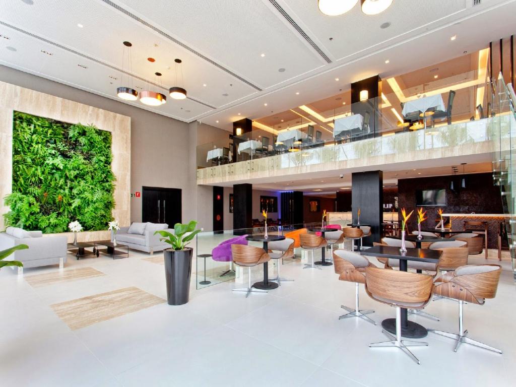 a lobby with a large plant on the wall at Golden Tulip São José dos Campos in São José dos Campos