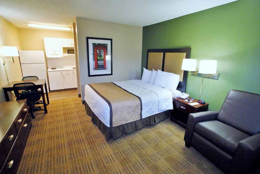 a hotel room with a bed and a chair at Suburban Studios Winston-Salem near Hanes Mall in Winston-Salem