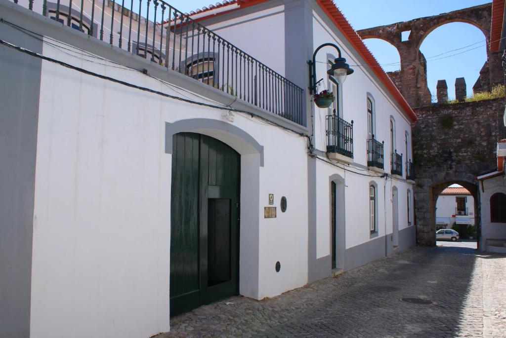 ein weißes Gebäude mit einer grünen Tür und einer Treppe in der Unterkunft Casa da Muralha de Serpa in Serpa
