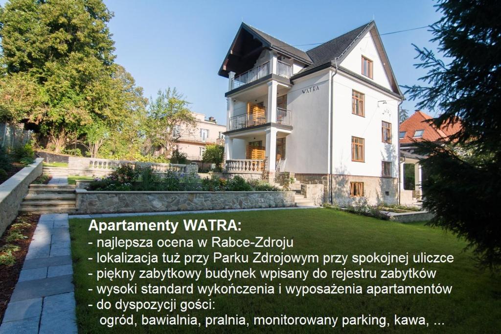 a white house with a sign in front of it at Apartamenty Watra in Rabka