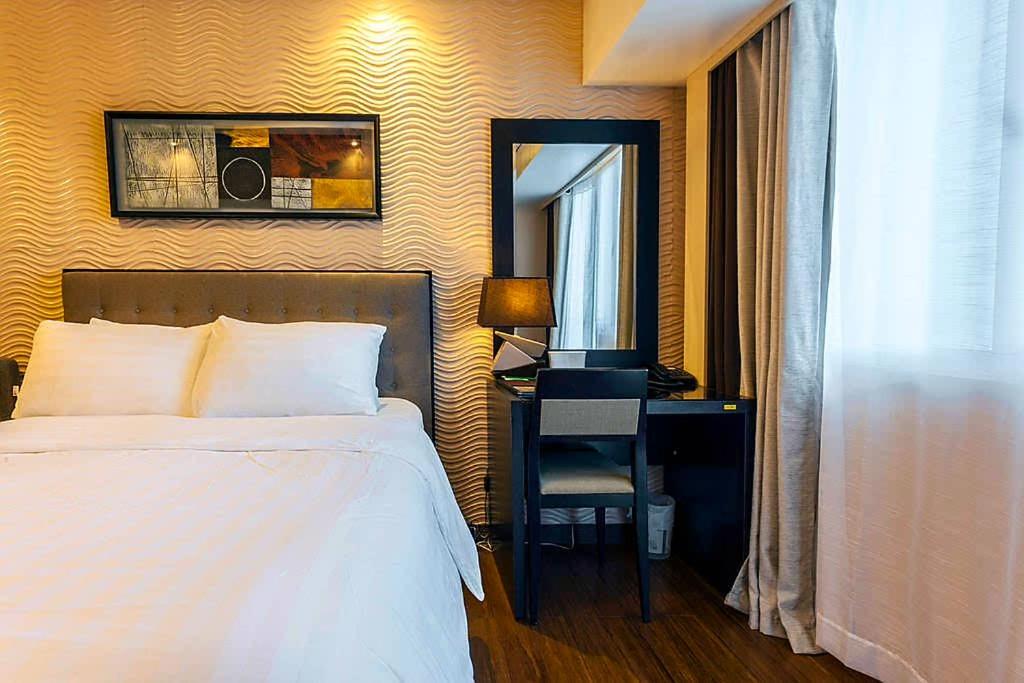 a bedroom with a bed and a desk and a mirror at Relaxing Wind in Tagaytay