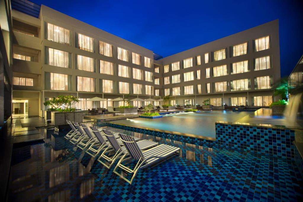 バンガロールにあるOakwood Residence Whitefield Bangaloreのホテルの前にラウンジチェア付きのプールがあります。
