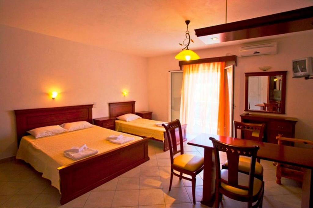 a bedroom with two beds and a table and a dining room at Sideris Lambros Rooms in Parga