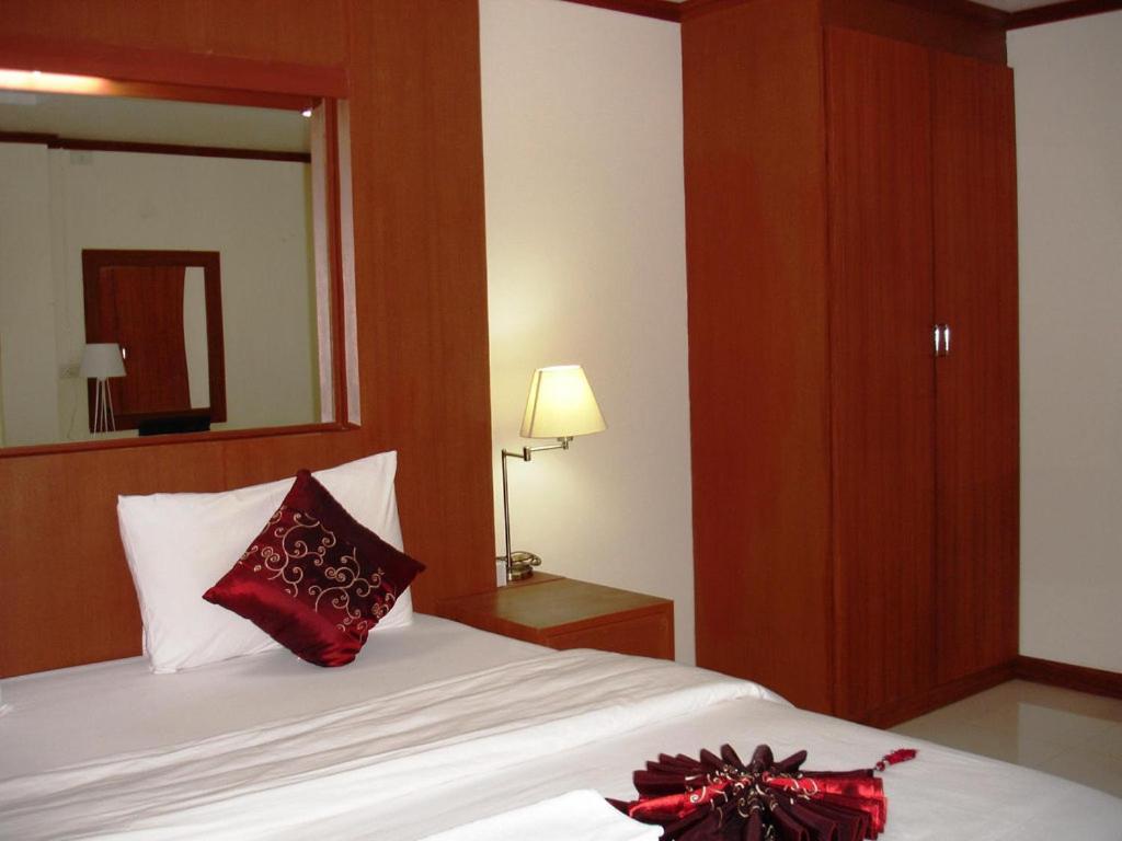 - une chambre avec un lit doté d'un oreiller rouge et d'un miroir dans l'établissement Chinathip Yusabuy, à Nan