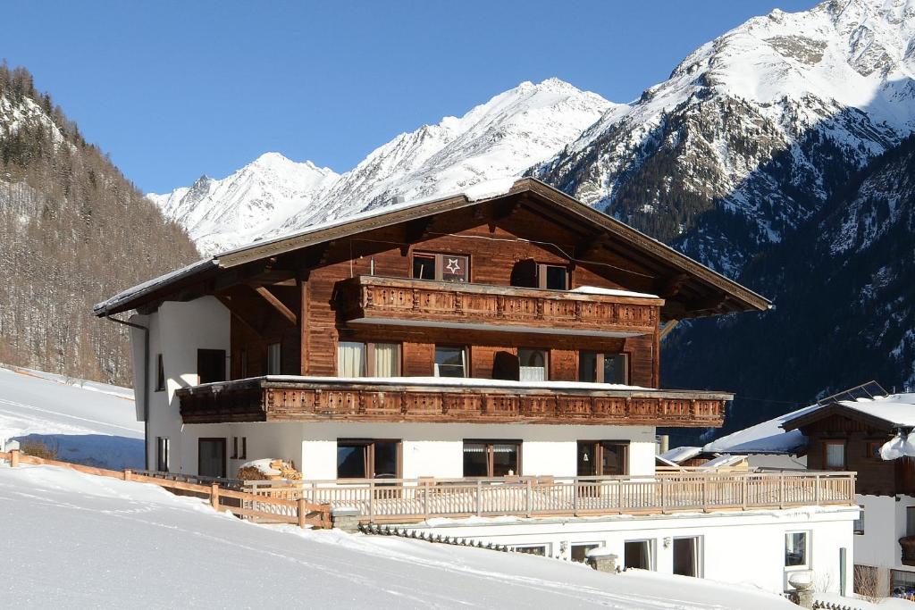 a building with snow covered mountains in the background at Ferienhof Riml in Sölden