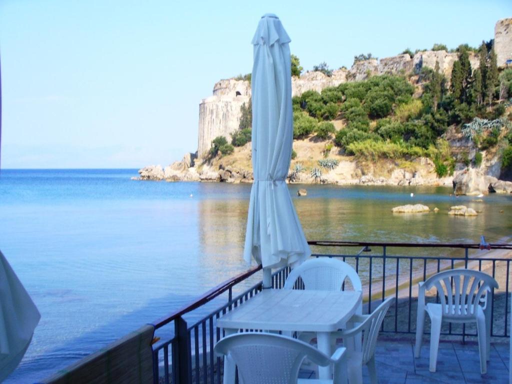 una mesa y sillas blancas y una sombrilla en el balcón en Xenios Zeus Rooms, en Koroni