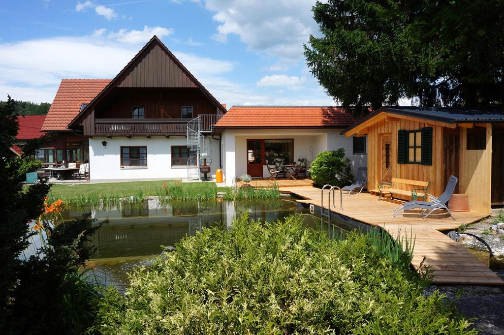ein Haus mit einem Teich davor in der Unterkunft Pension Wolkenreich in Oberhaag