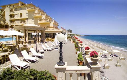 una spiaggia con sedie e un edificio e l'oceano di Hellenia Yachting Hotel & SPA a Giardini Naxos