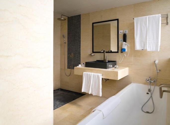 a bathroom with a tub and a sink and a mirror at Hotel Adef in Oran