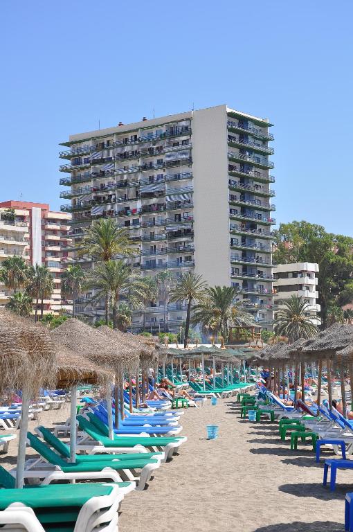 a row of beach chairs and umbrellas on a beach at Apartamentos Mediterraneo in Marbella