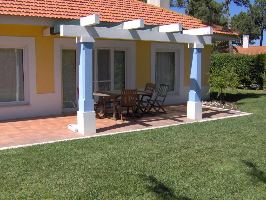 pergola ze stołem i krzesłami na patio w obiekcie Aldeamento Turistico Casas da Comporta w mieście Comporta