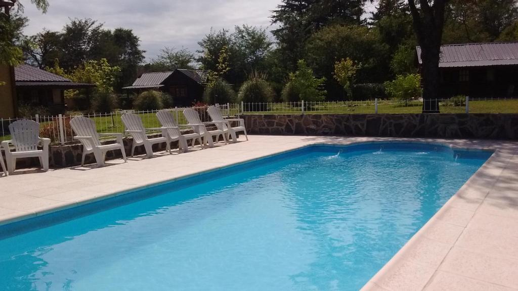 una piscina con sillas y una piscina en Estilos Argentinos en Los Reartes