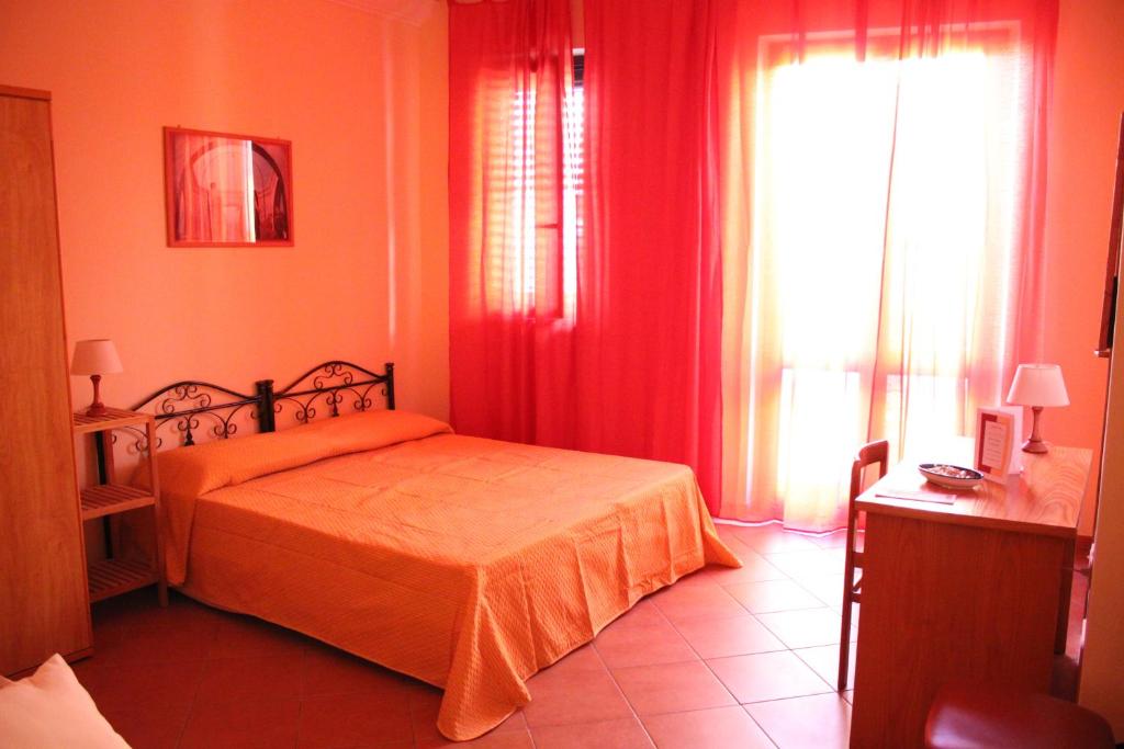 a bedroom with a bed with orange sheets and a window at La casa di nonna Rosa in Isola delle Femmine