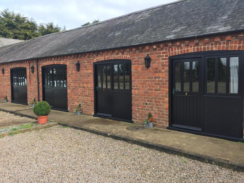 a brick building with black doors and windows at The Stables at Whaplode Manor in Holbeach