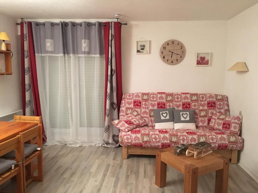 un salon avec un canapé et une horloge au mur dans l'établissement Studio Cabine Les Balcons du Soleil, à Font-Romeu-Odeillo-Via