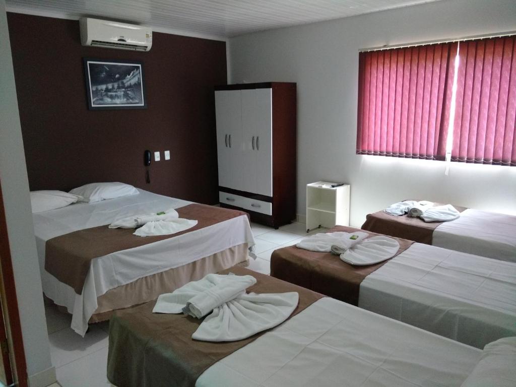 a hotel room with three beds with towels on them at Euro Plaza Hotel - Próximo ao Aeroporto de Goiânia, Santa Genoveva in Goiânia