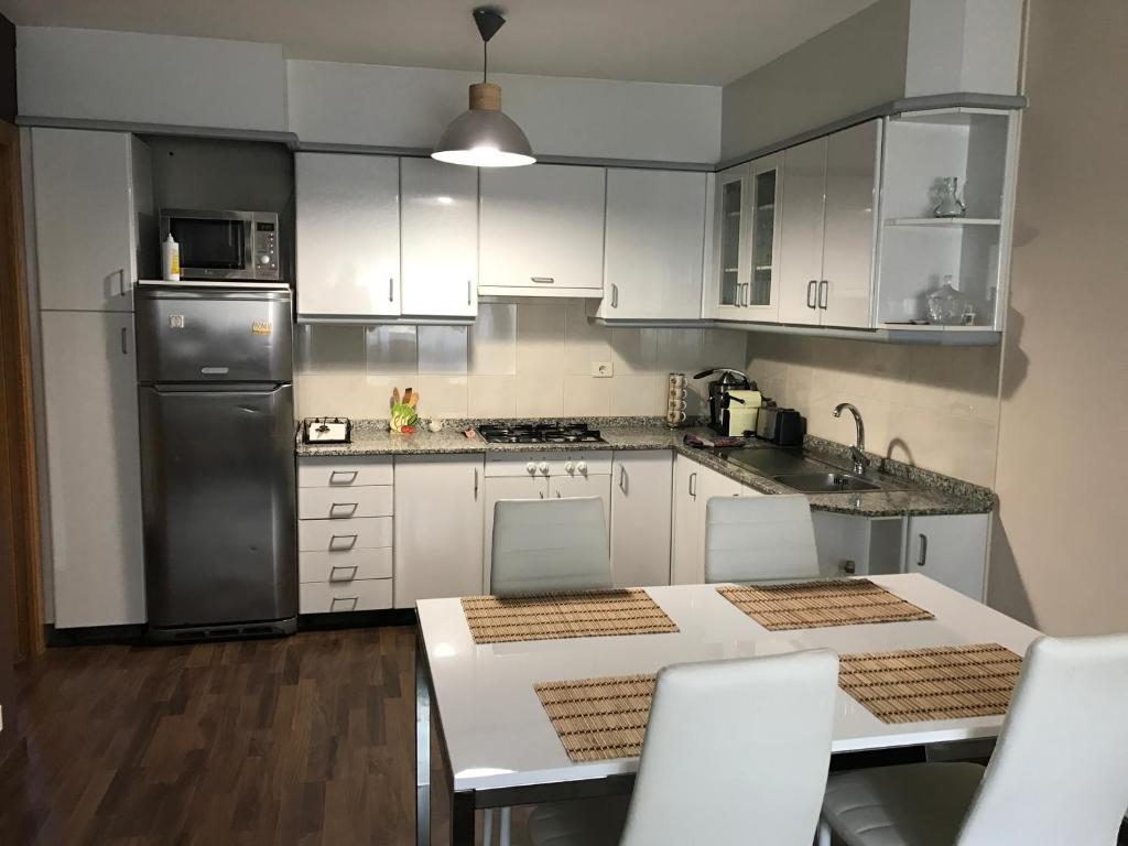 una cocina con armarios blancos y electrodomésticos de acero inoxidable en Piso Camino De Santiago, en Sarria
