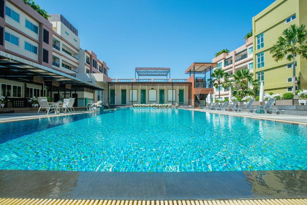 uma grande piscina com água azul num edifício em Jasmine Resort Hotel and Serviced Apartment em Si Racha